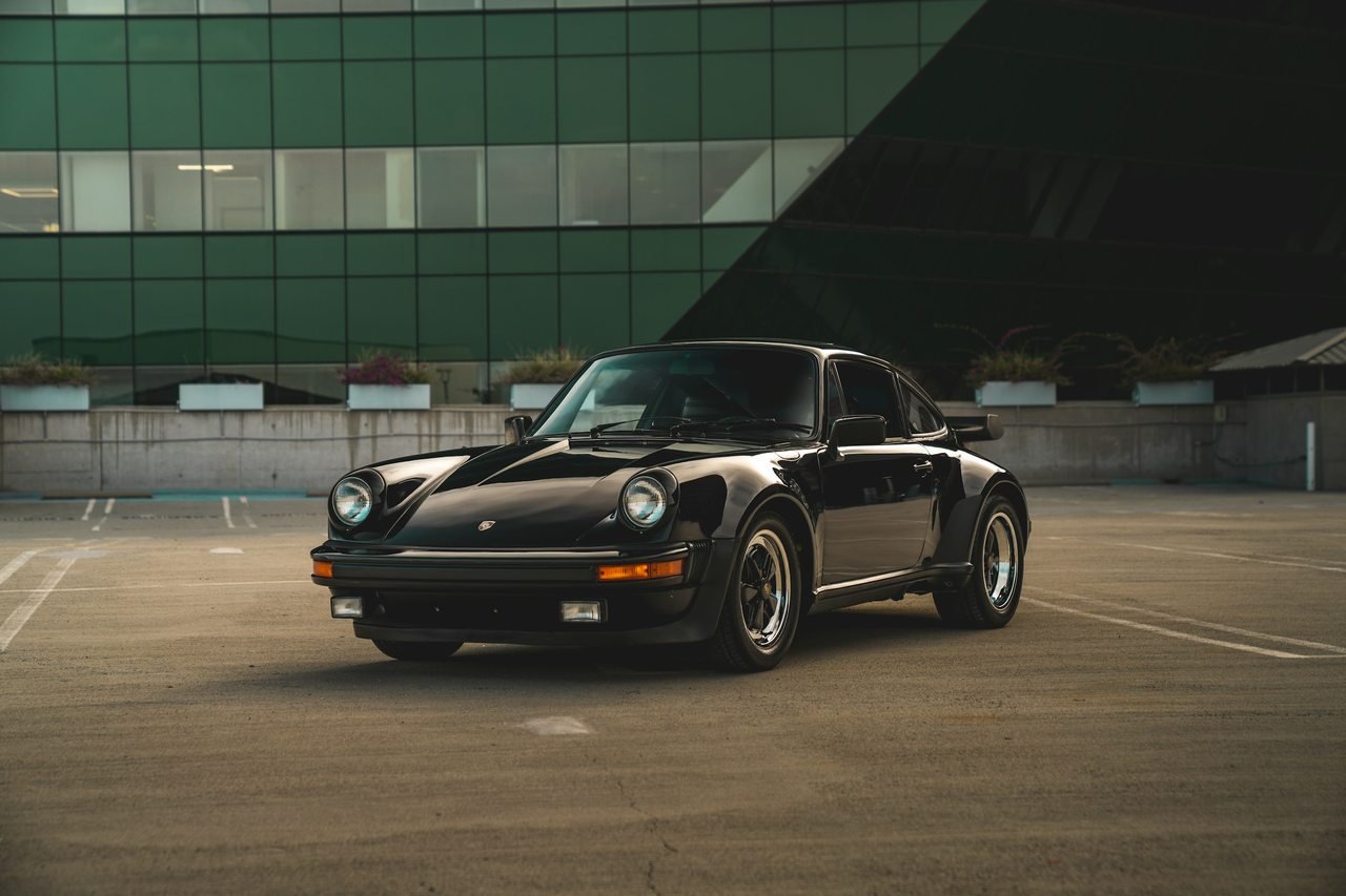 Black classic European sports coupe in a quiet paved courtyard.